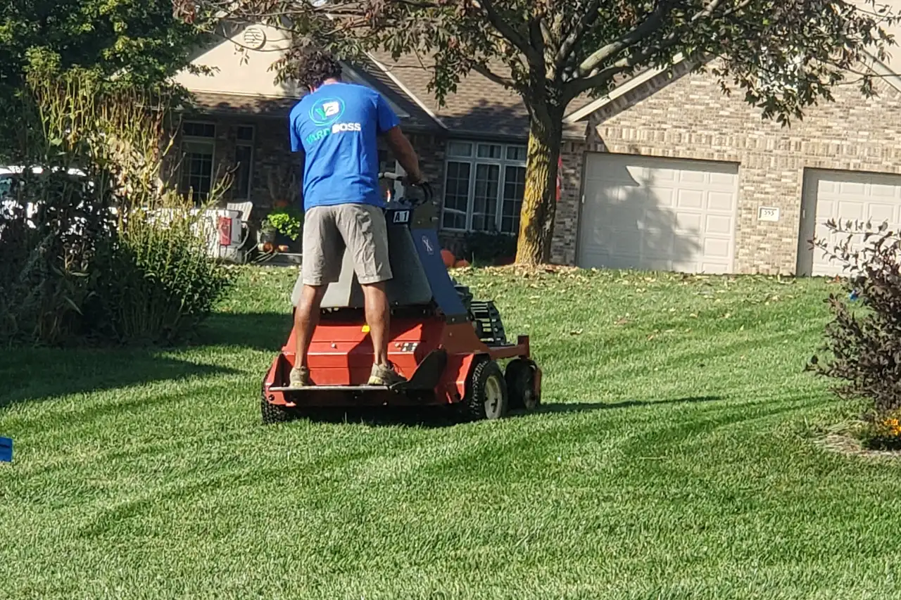 A Yard Boss technician treating a residential front lawn with a ride-on spreader in Lincoln, Nebraska